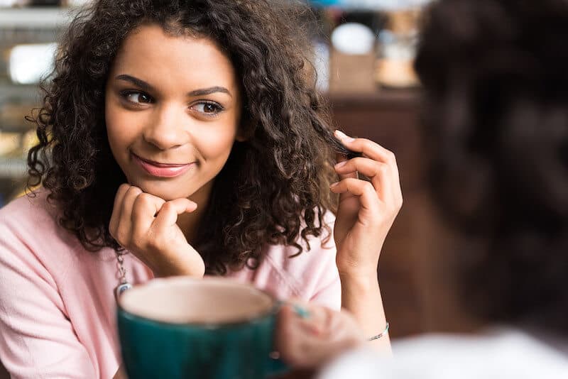 Girl playing with her hair while listening to a guy speaking